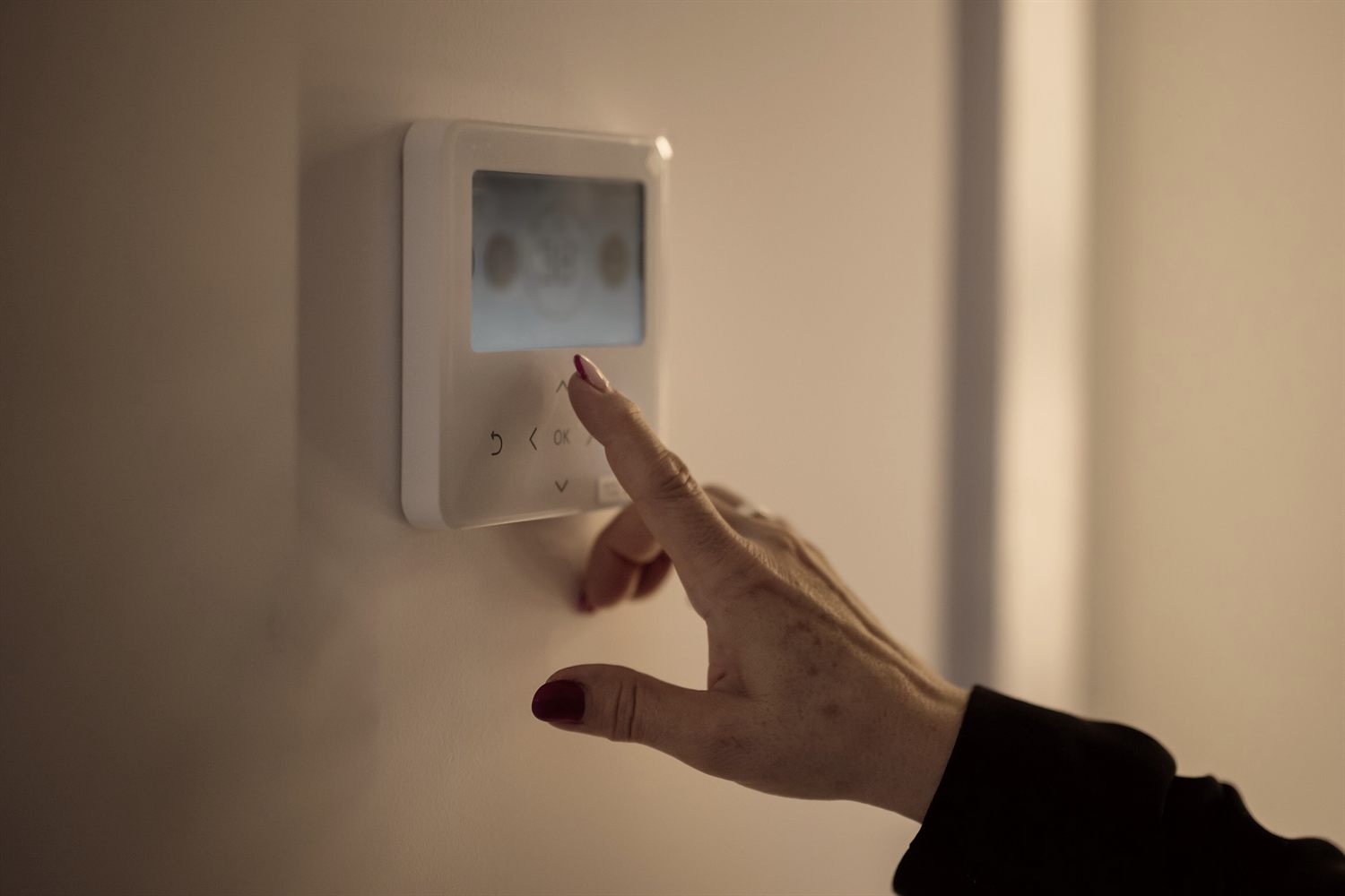A homeowner adjusting a wall thermostat